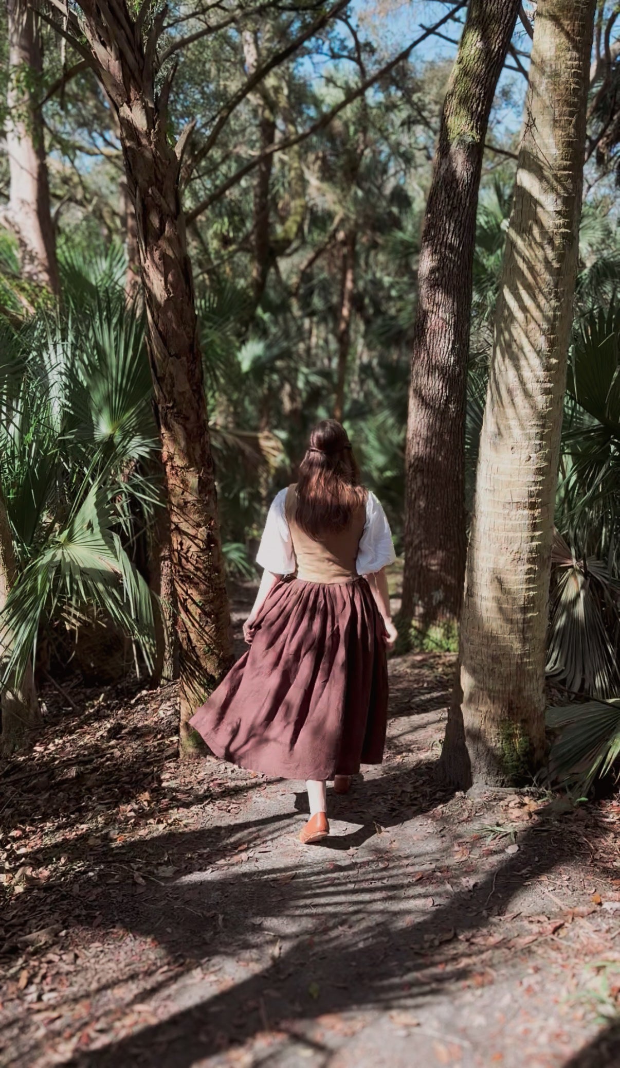 Woman walking through a forest with trees and underbrush